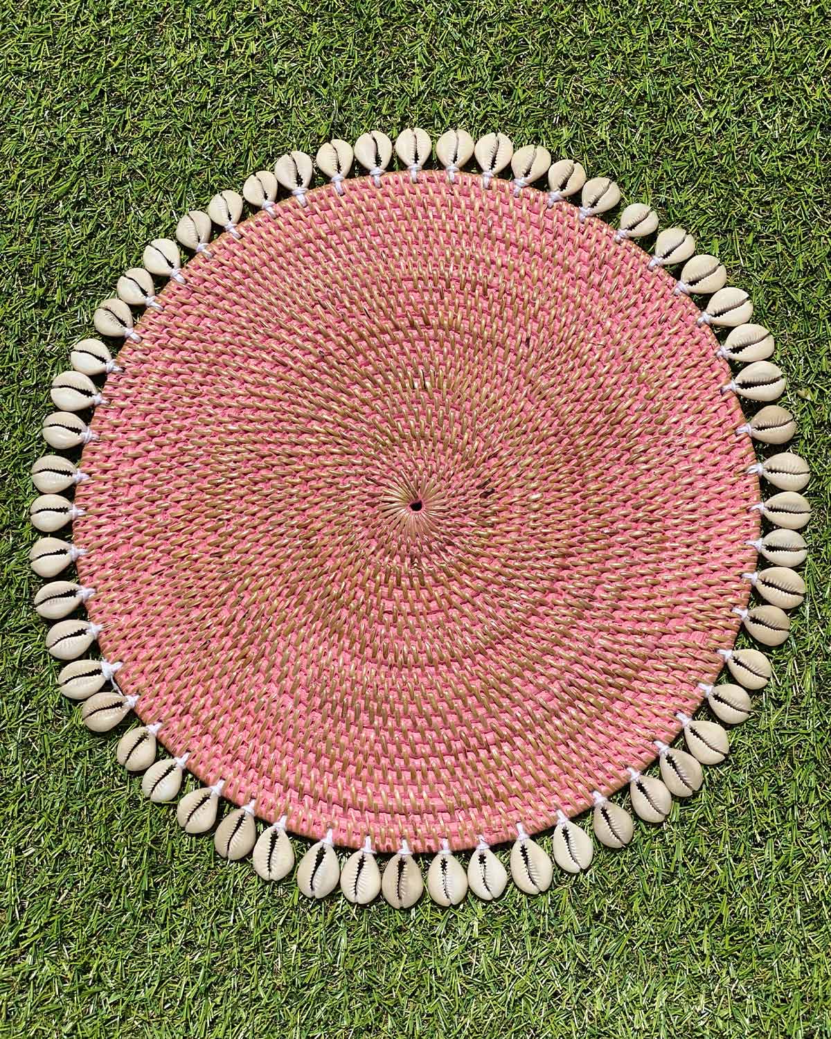 Table placemat in coloured pink rattan edged with sea shells.