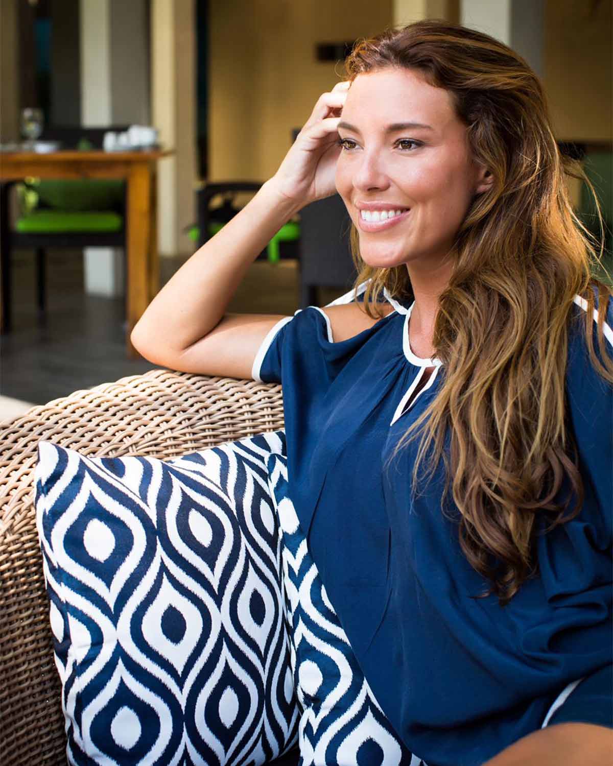 Woman smiling with White Ginger boutiques outdoor cushions part of their homeware collection.