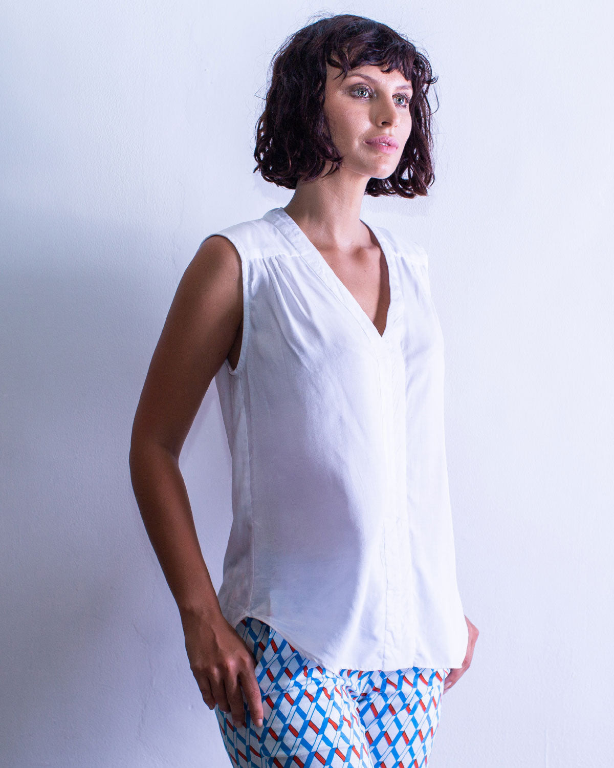 Woman in a sleeveless shirt style top, in the colour white. A womans fashion staple.